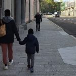 Madre e figlio che camminano per strada mano nella mano