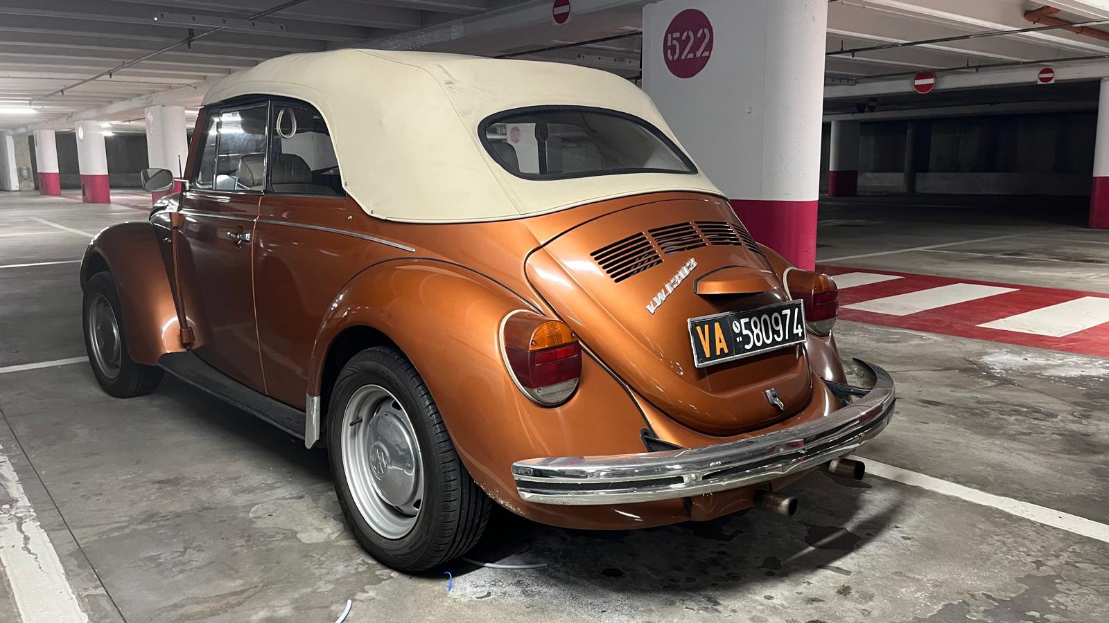 In un parcheggio, tra tutte le macchine, spicca un vecchio maggiolino