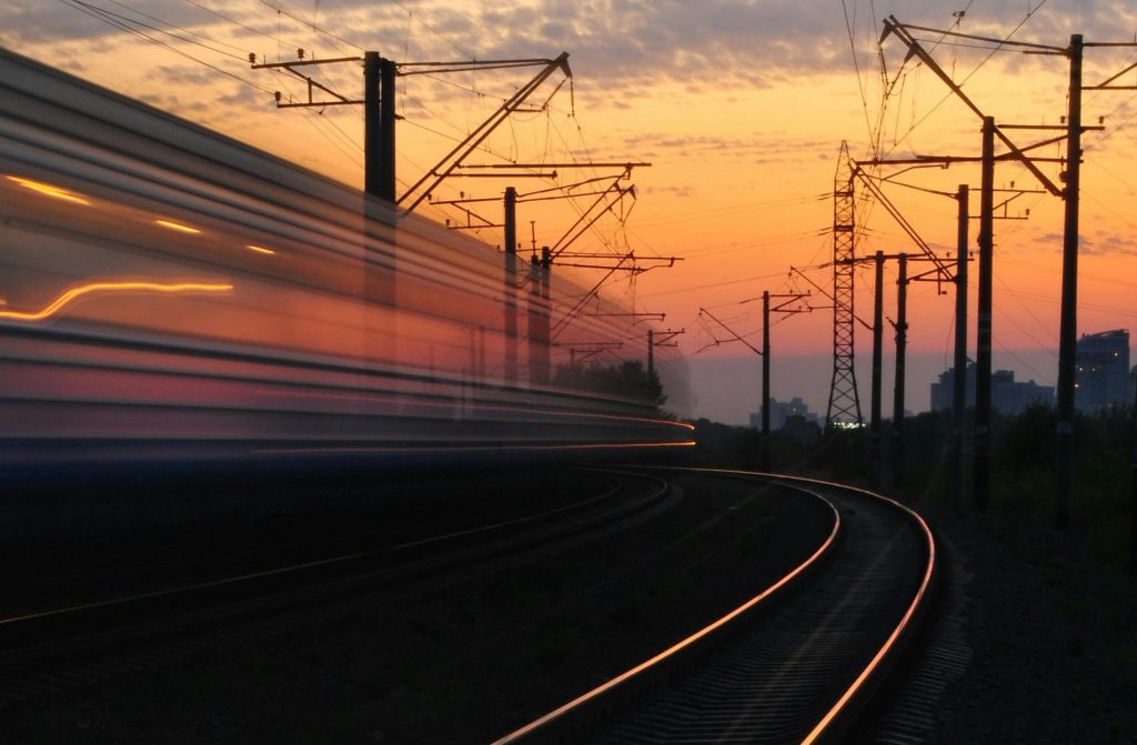 Foto con treno in velocità al tramonto.